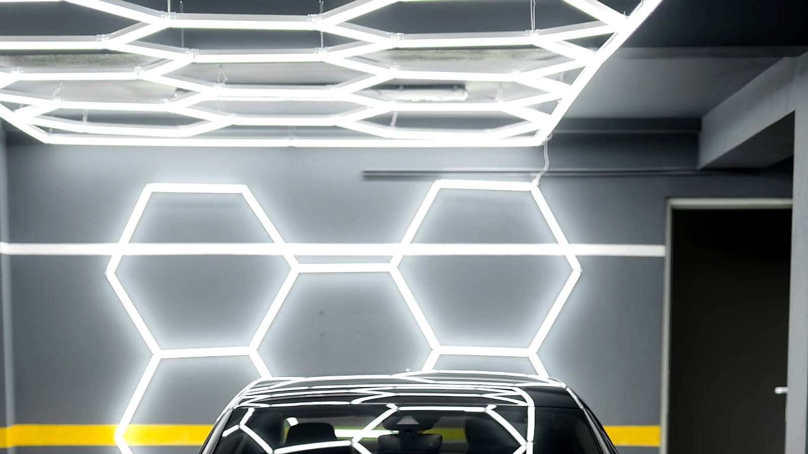 Mașină sport premium neagră în atelierul de detailing din Brașov, sub iluminarea hexagonală